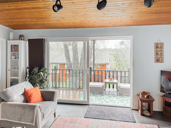 A living room with a sofa, a television, a bookshelf, and a sliding glass door leading to an outdoor patio.