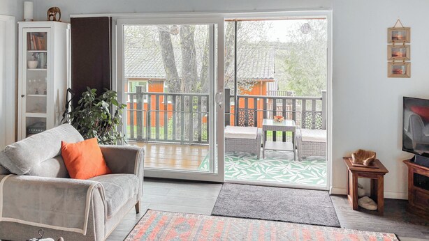 A living room with a sofa, a television, a bookshelf, and a sliding glass door leading to an outdoor patio. - 1 bedroom accommodation in Bideford (Bideford)