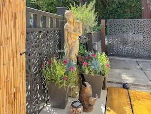 A garden with a statue, potted plants, and a decorative fish.