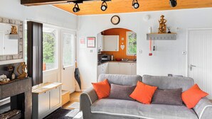 A cozy living area with a grey sofa, wooden ceiling, and a kitchen in the background. - 1 bedroom accommodation in Bideford (Bideford)