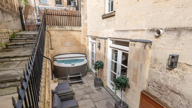 Een binnentuin met een jacuzzi, zitgedeelte en potplanten.