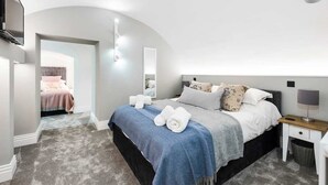 Een slaapkamer met een bed, nachtkastje en een aan de muur bevestigde televisie.