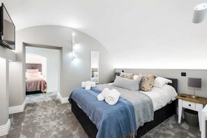 Relax in this serene bedroom with a large bed, bedside table, and mirror.