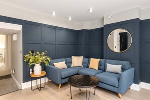 Relax in this stylish living room with a dark blue sofa, round coffee table, and elegant vase on a side table.