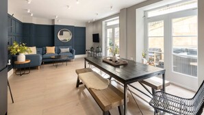 Een moderne woonkamer met een bank, een salontafel en een eettafel met banken.