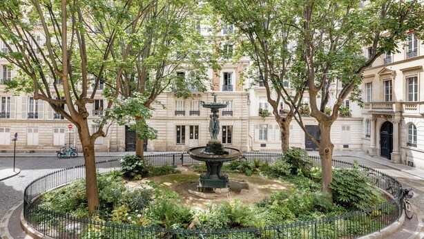 A circular park with a fountain, surrounded by trees and a fence. - Trevise (Paris)