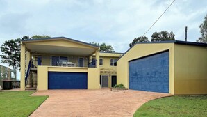 A two-story house with a blue garage door, a covered patio, and a well-maintained lawn. - The Sandcastle at Burrum Heads (Burrum Heads)