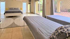 A hotel room with a bed, a sofa, a window with a view, and a door leading to the outside. - The Sandcastle at Burrum Heads (Burrum Heads)