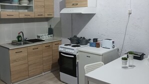A compact kitchen with wooden cabinets, a stove, oven, and a small dining table with chairs.