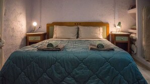 A bed with a quilted blue blanket, two pillows, and two bedside tables with lamps.