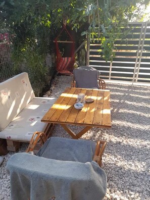 A wooden table with a bowl and a chair with a blanket.