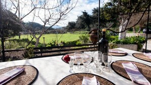 Un espace de restauration en plein air avec une table dressée pour quatre personnes, offrant une vue sur un paysage pittoresque.