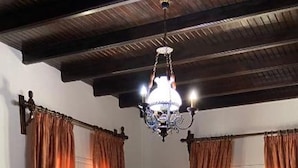 Un coin repas avec une table dressée pour six personnes, entouré de rideaux, d’un lustre et d’une horloge murale.