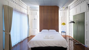 Ein ordentlich eingerichtetes Hotelzimmer mit einem großen Bett, einer Wand mit Holzvertäfelung und einer grünen Tür.