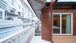 Ein Balkon mit Blick auf eine Stadtansicht, eine Holztür und eine Glastür zum Raum.