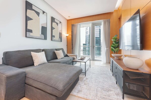 A modern living room with a grey sectional sofa, a small coffee table, and a TV on a wooden cabinet.