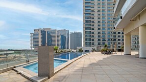 Ein Poolbereich auf dem Dach mit Blick auf hohe Gebäude, einem Pool und Sitzgelegenheiten im Freien.