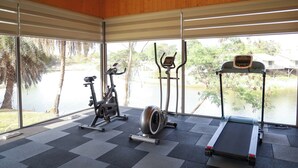 A gym with exercise equipment and large windows overlooking a body of water. - Praveg Rezort Kachigam (Daman)