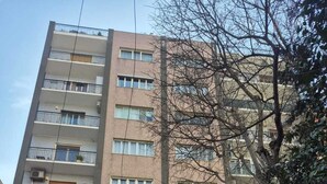 Ein mehrstöckiges Gebäude mit Balkonen, ein Geschäft mit Beschilderung und parkende Autos auf der Straße.
