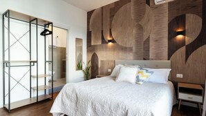 Ein Schlafzimmer mit Bett, Nachttisch, einer Holzwand mit abstrakten Mustern, einem Kleiderschrank und einer Pflanze.