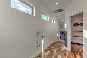 Enter a bright and airy hallway leading to a stylish bedroom with a comfortable bed and modern entertainment features.