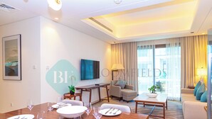 Une chambre d’hôtel avec un coin repas, un canapé et une grande fenêtre avec des rideaux.