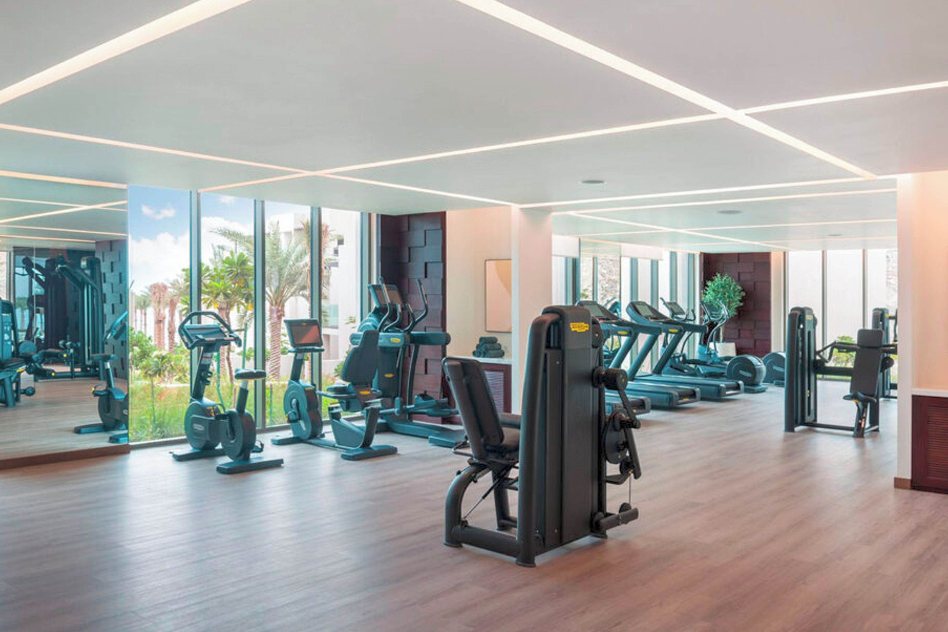 Una palestra con diverse attrezzature per l'allenamento, ampie finestre e un pavimento in legno.