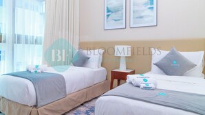 Une chambre d’hôtel avec deux lits, une table de chevet et une fenêtre avec des rideaux.