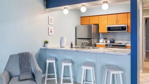 Een moderne keuken met een centraal eiland, barkrukken en een zithoek met een stoel.