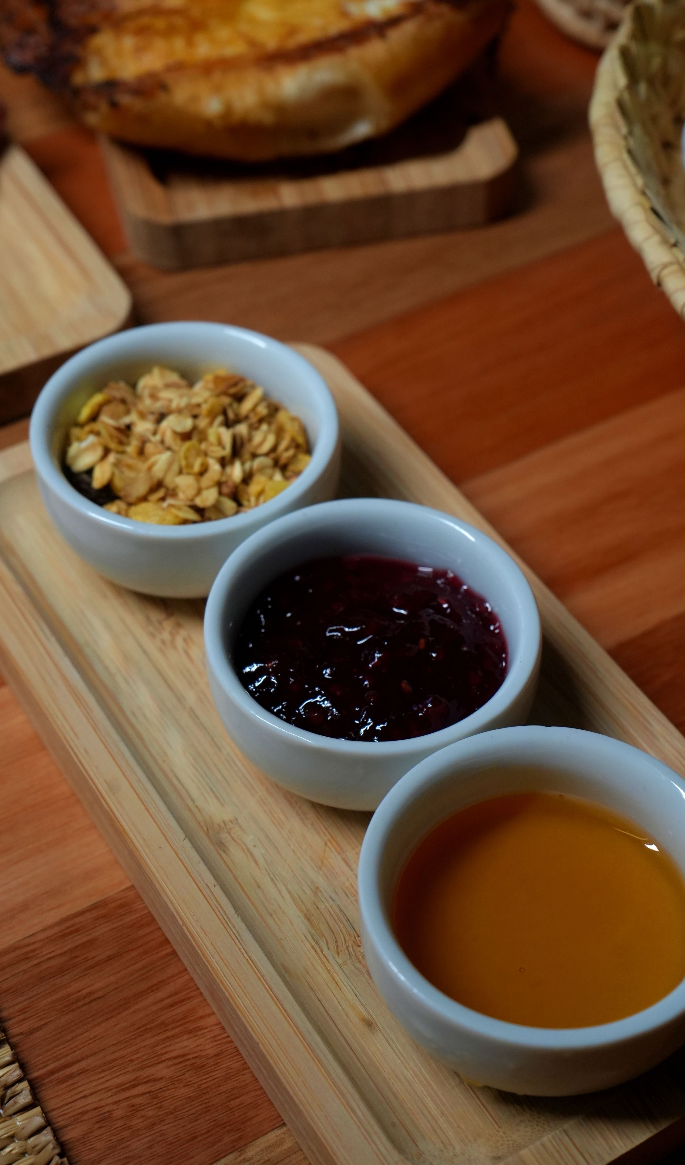 A wooden serving board with three bowls containing different food items.