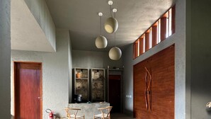 A modern living room with a concrete floor, wooden furniture, a stone fireplace, and a view of the outside. - Oribá Chalé Boutique (Sao Miguel dos Milagres)