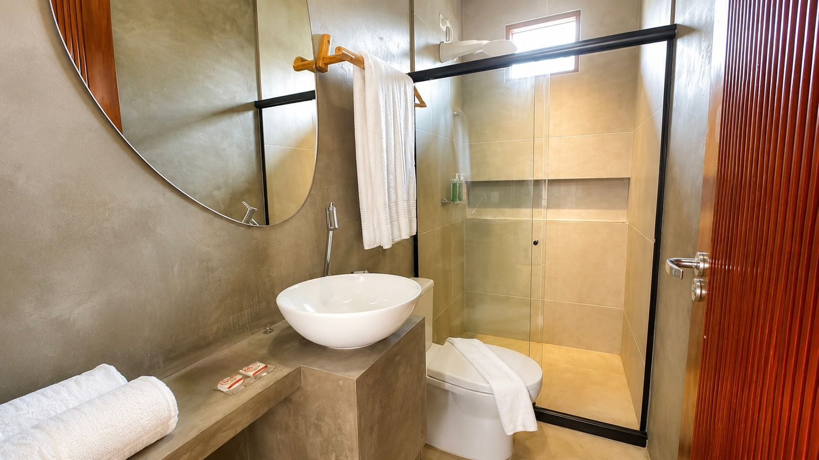 Une salle de bain moderne avec un grand lavabo sur pied, des toilettes et une douche à parois de verre.
