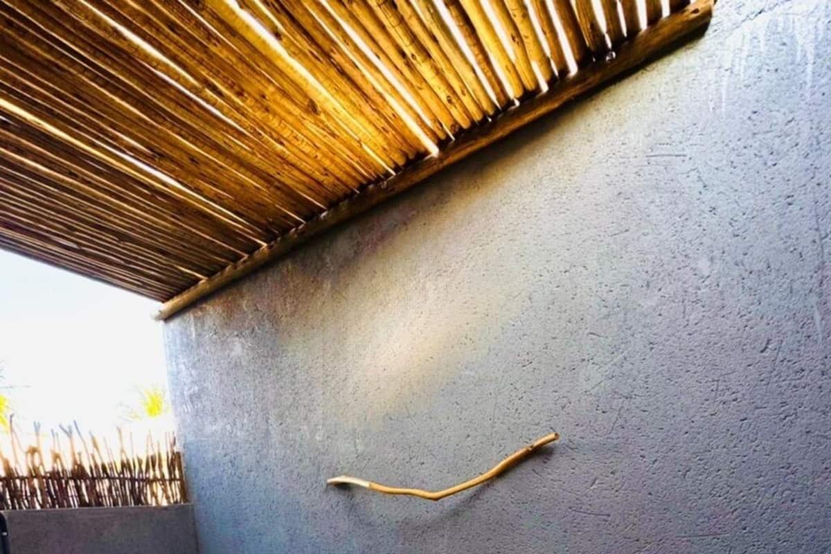 Eine Holzterrasse mit Whirlpool, einem Korbstuhl und einem kleinen Tisch mit einer Vase.