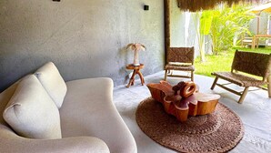 A modern living room with a sofa, a round wooden coffee table, and two wicker chairs. - Oribá Chalé Boutique (Sao Miguel dos Milagres)