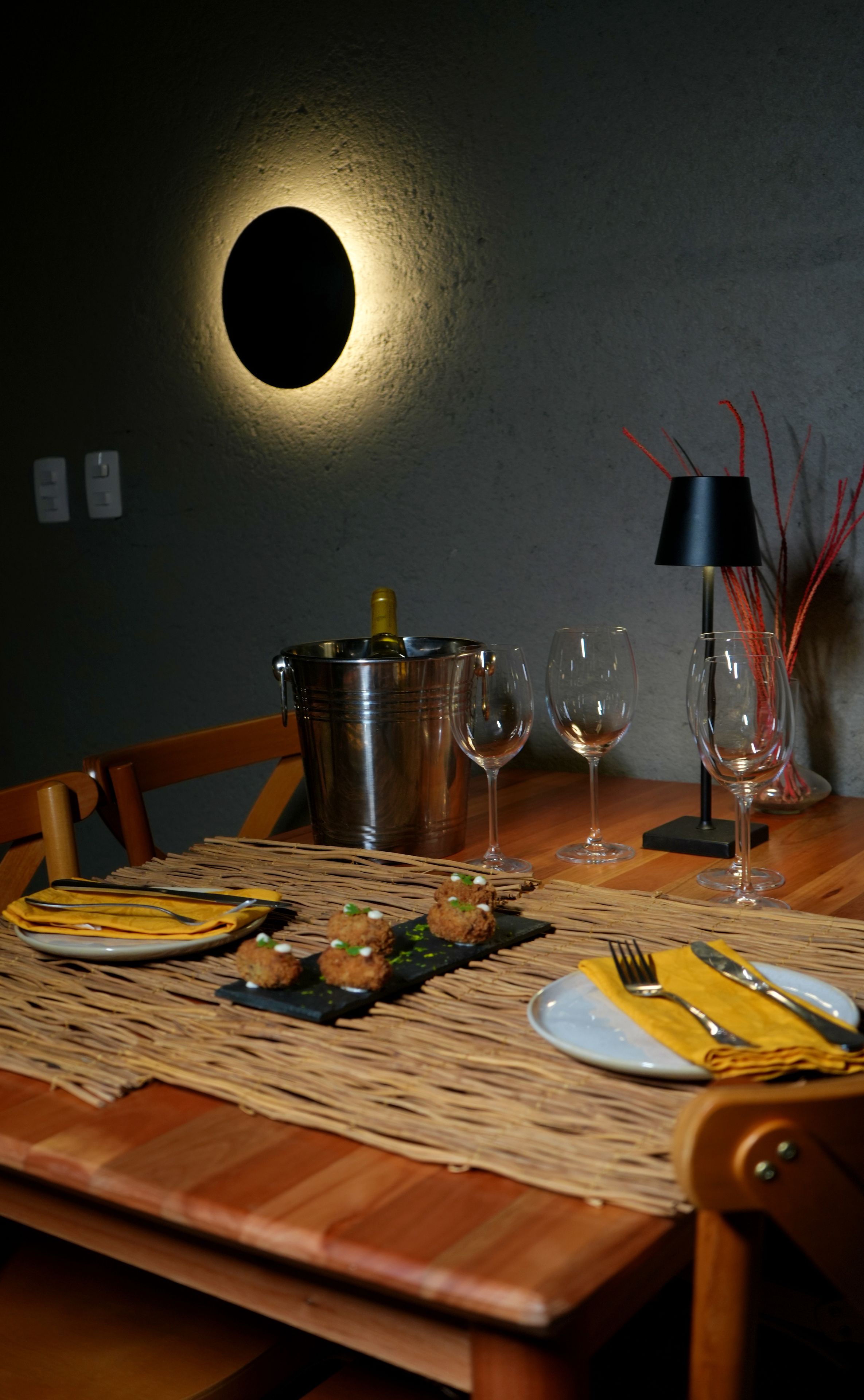 A dining table set with plates, cutlery, and glasses, with a bottle of champagne in a metal bucket.