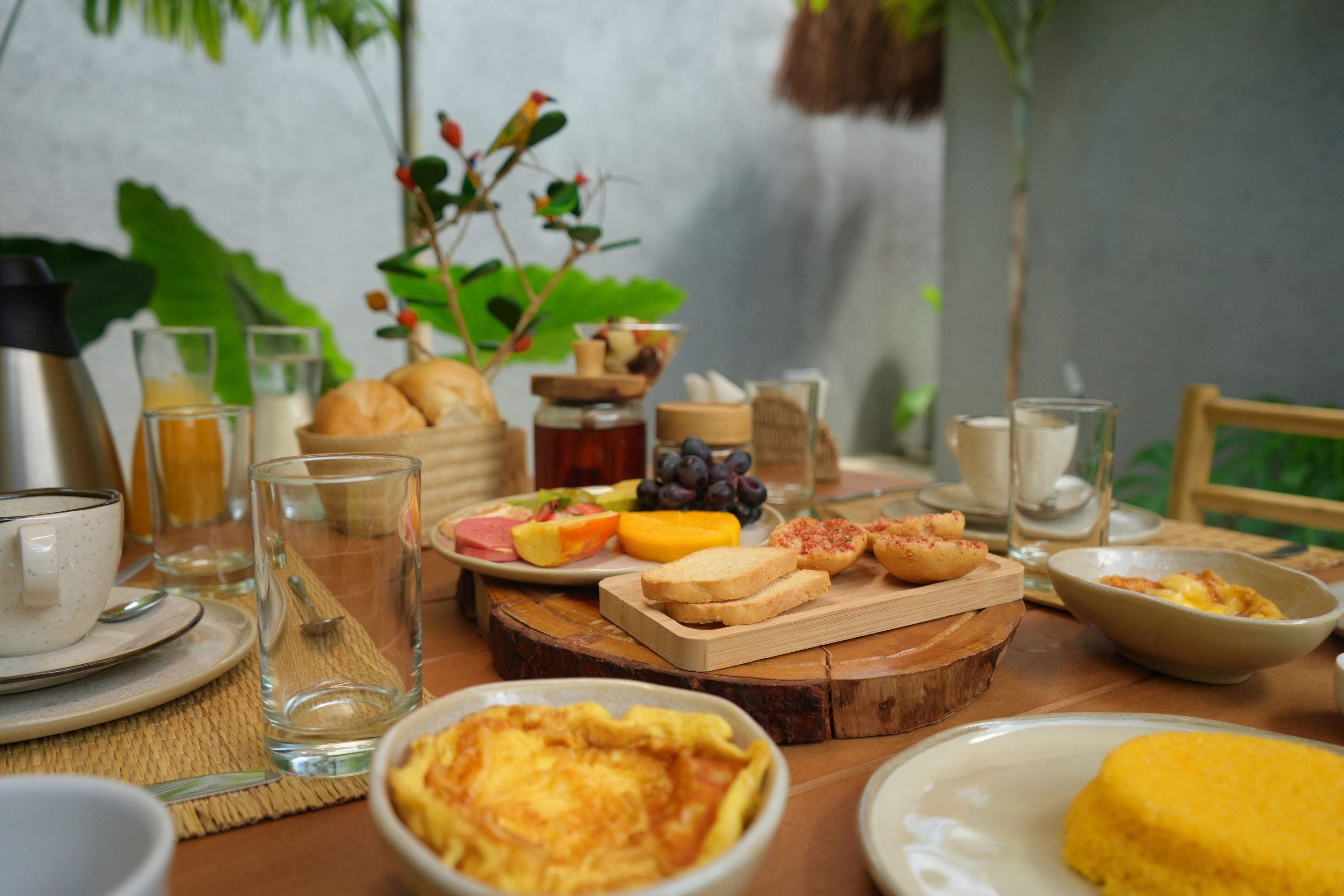 A breakfast setting with various food items and drinks on a wooden table.