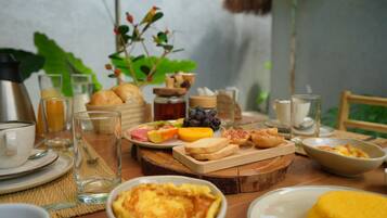A breakfast setting with various food items and drinks on a wooden table.