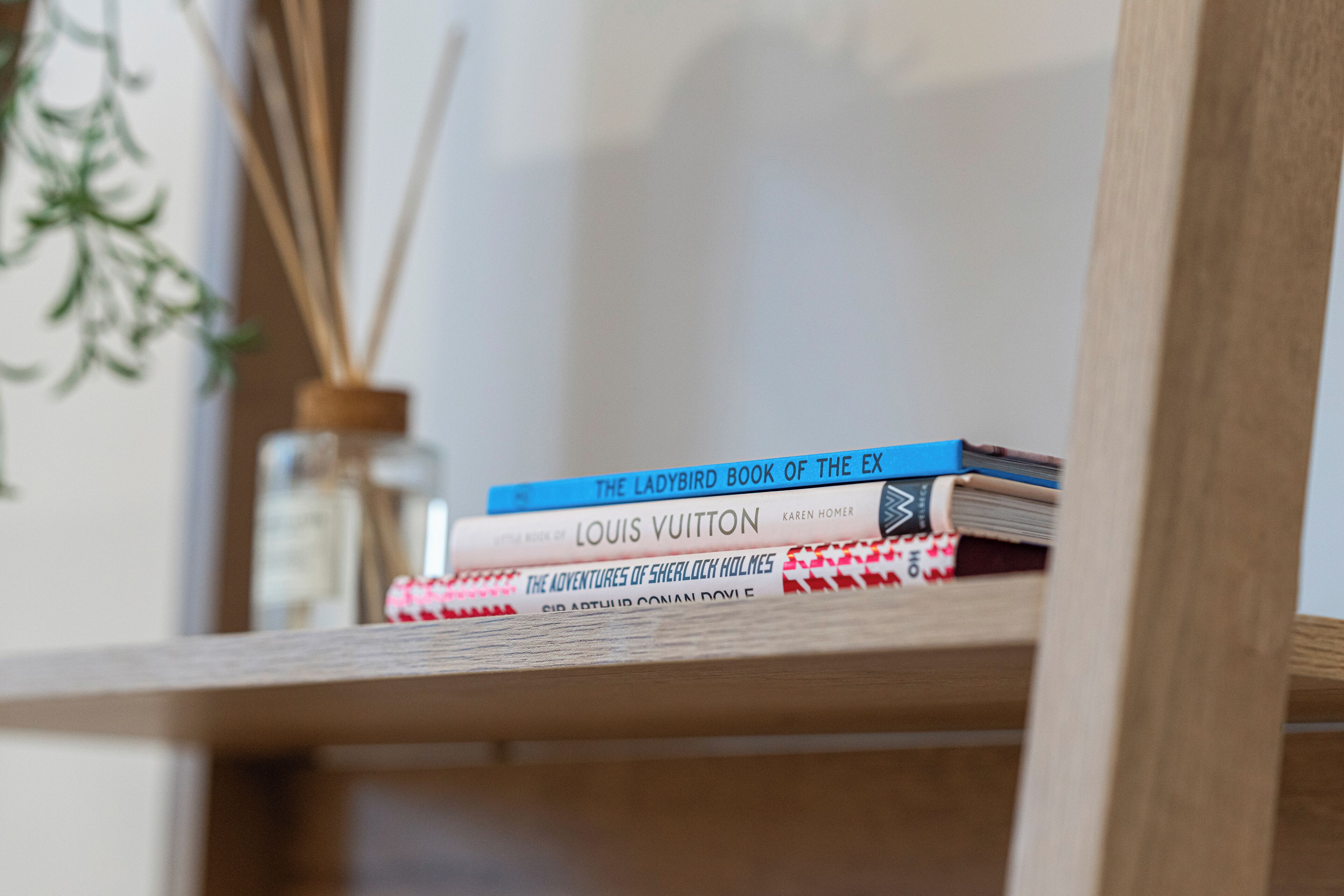 A stack of books on a wooden shelf.