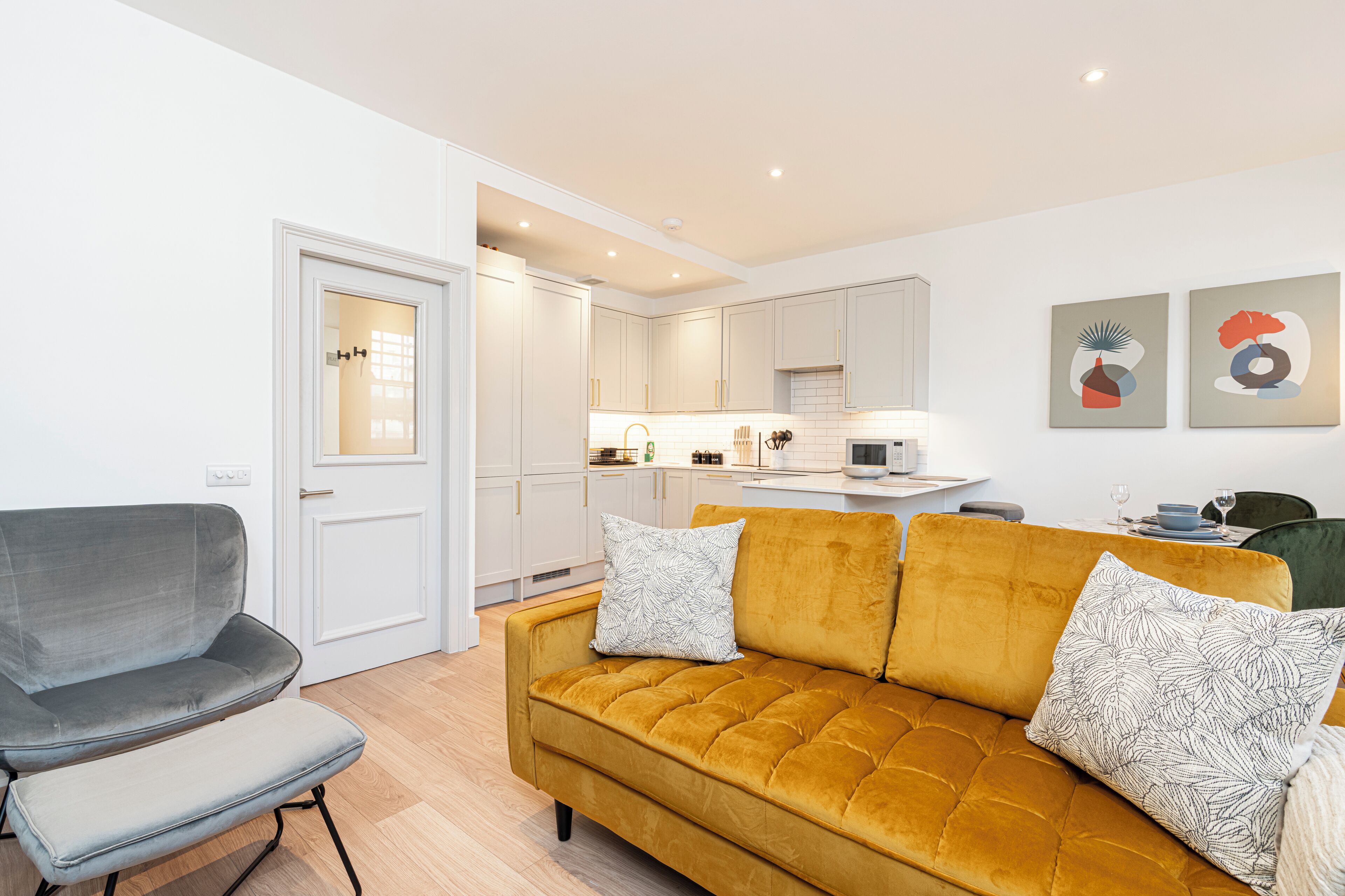 A modern living room with a sofa, a chair, and a kitchen in the background.