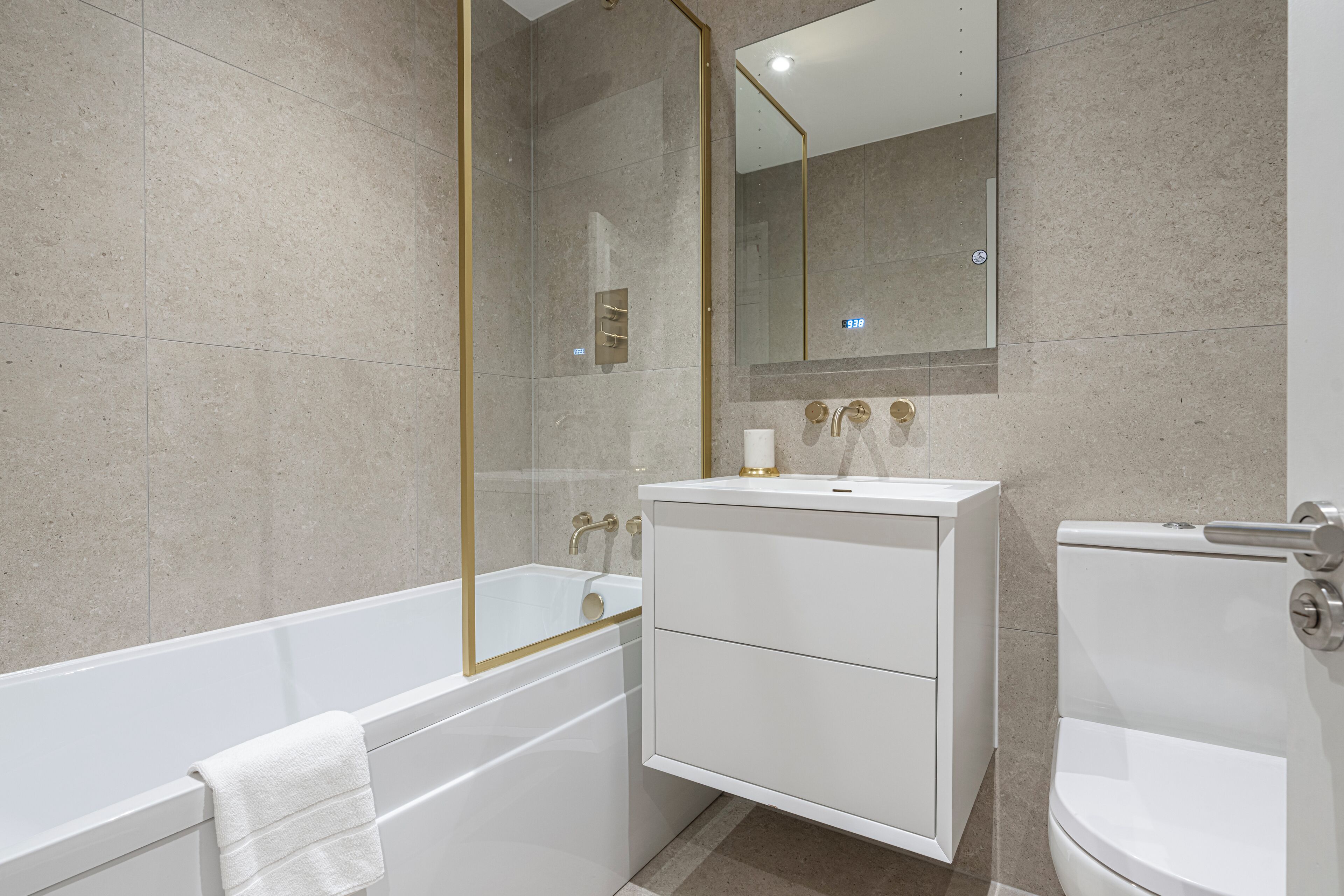 A modern bathroom with a bathtub, a toilet, and a vanity with a mirror.