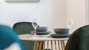 A dining table set with plates and glasses, a green chair, and a gold chair. - JOIVY Stylish 1 bed flats in Soho (London)