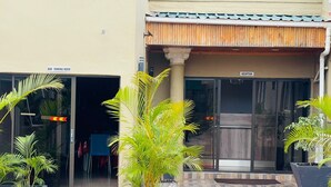 Entrada de un hotel con recepción, bar restaurante y plantas en macetas.