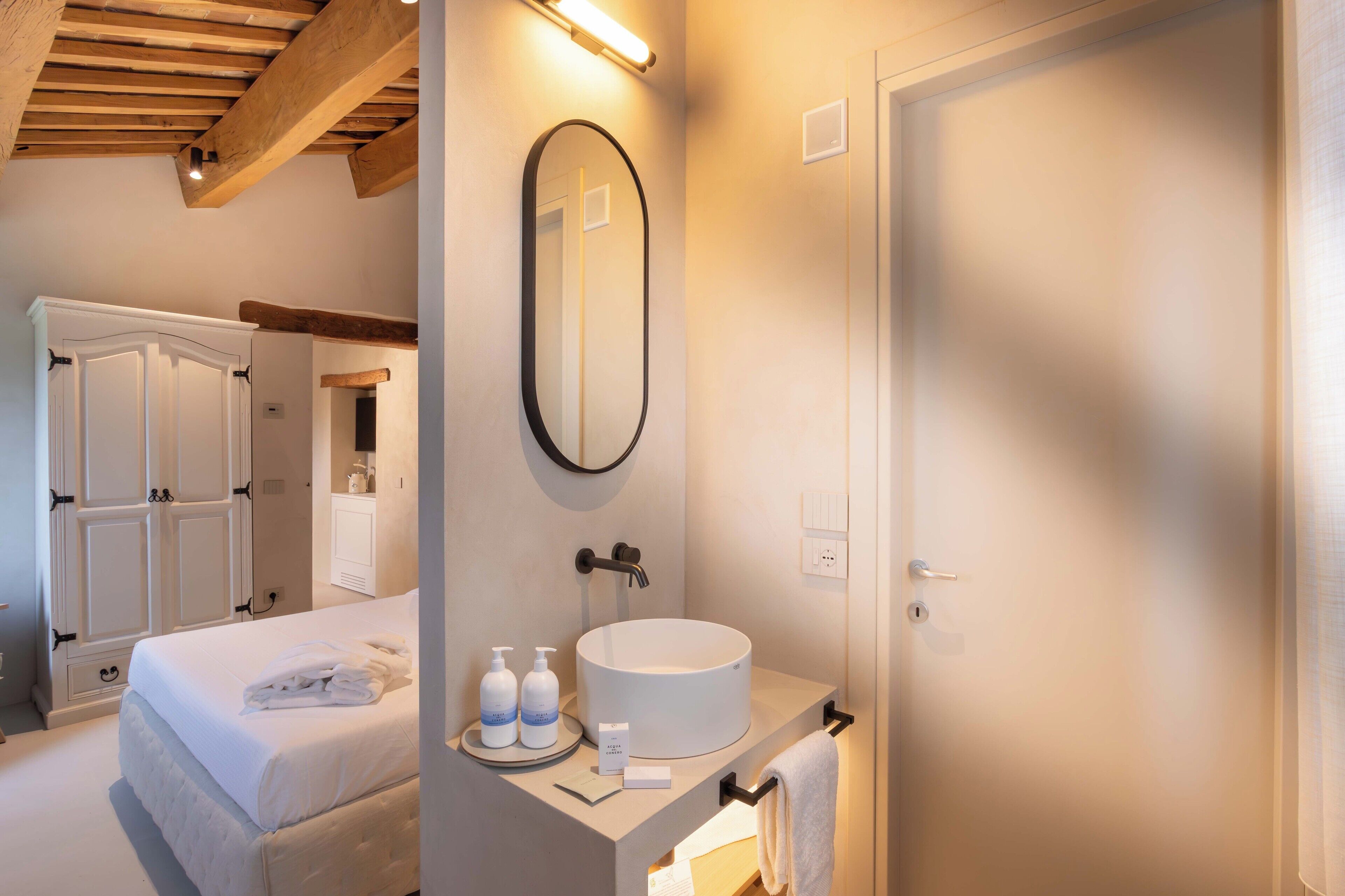 Habitación de hotel con cama, lavamanos redondo, espejo y armario.