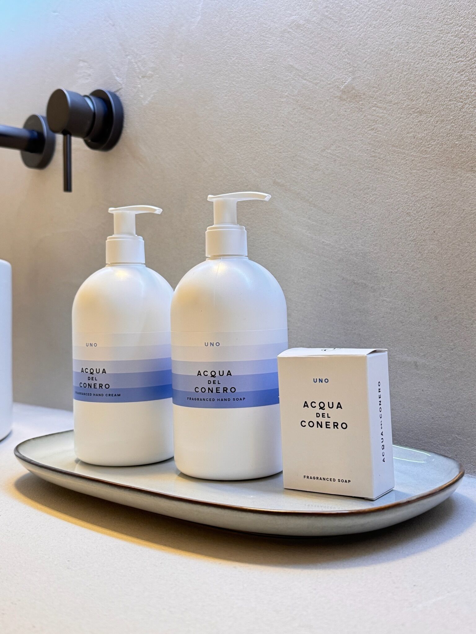 Two bottles of hand soap and a box on a ceramic plate.
