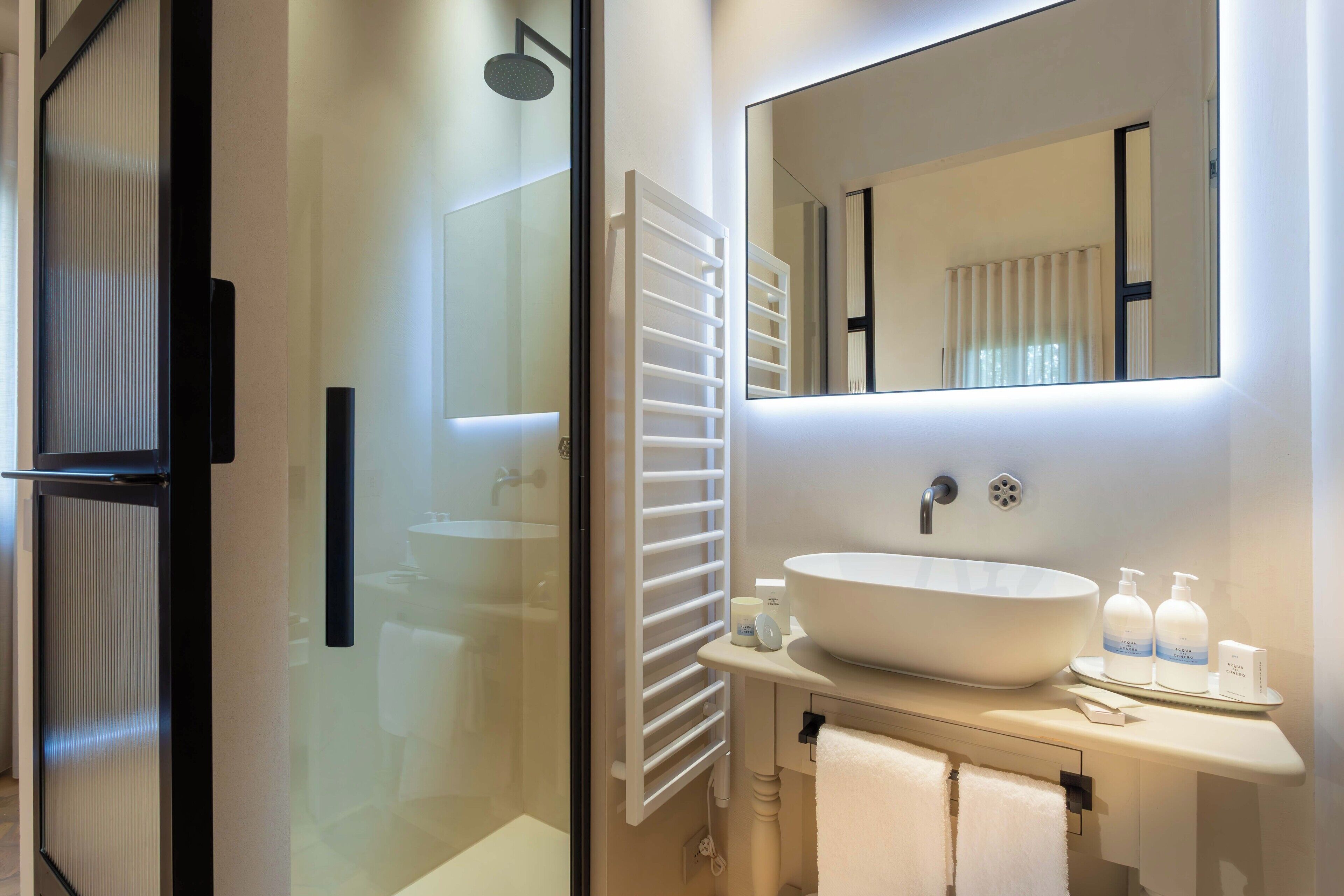 A modern bathroom with a large white sink, a mirror, and a glass shower enclosure.