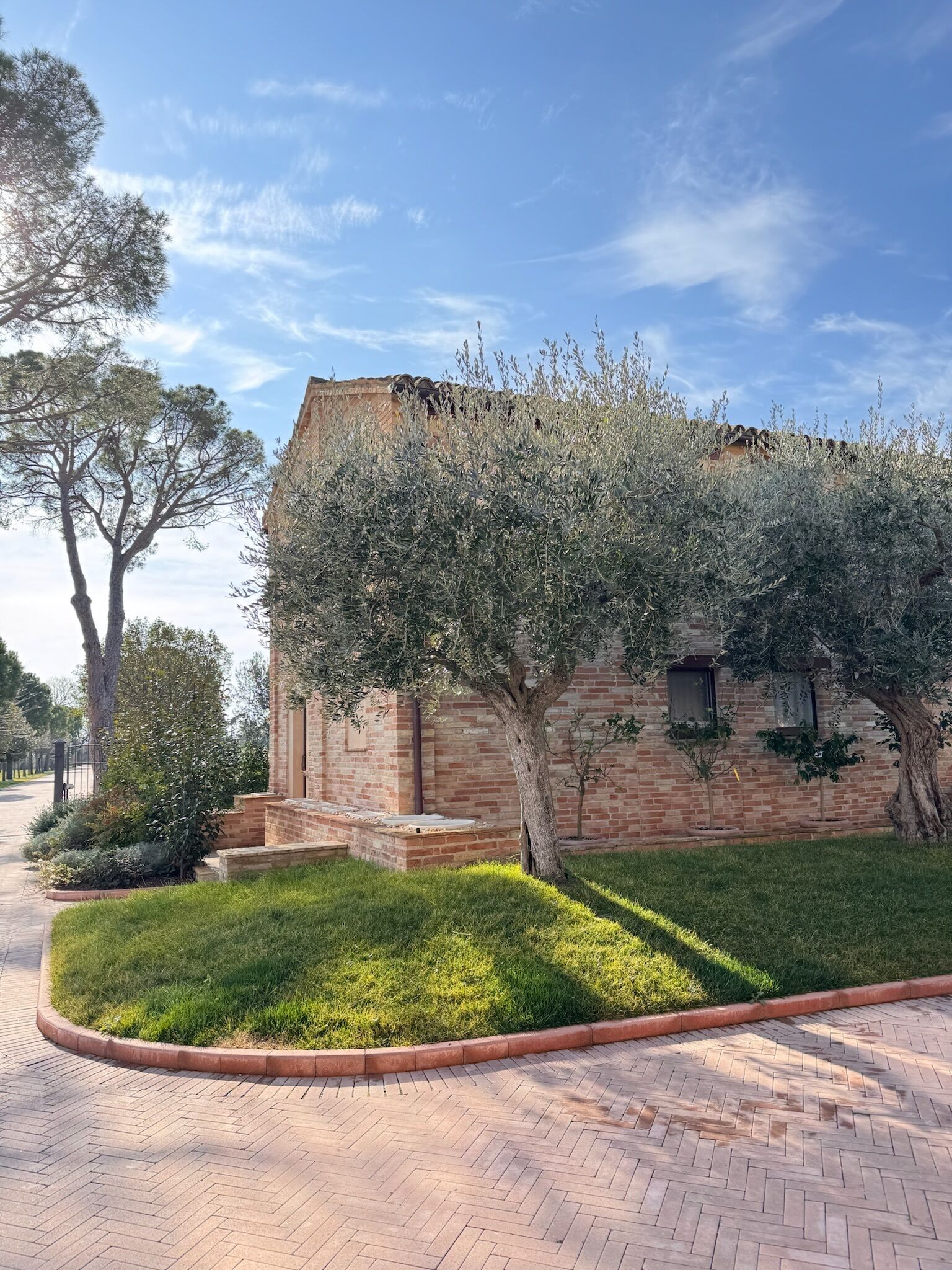 Un edificio in mattoni con un giardino, un vialetto lastricato e un albero.