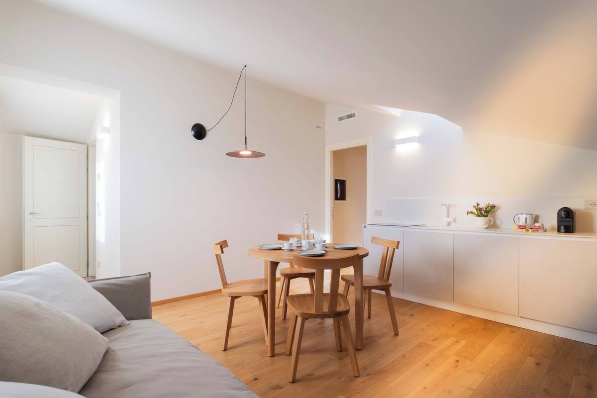 Una cocina moderna con armarios de madera, una mesa de comedor con sillas e iluminación colgante.