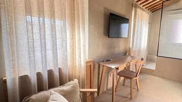 Um quarto aconchegante com uma cama, uma escrivaninha e uma televisão.