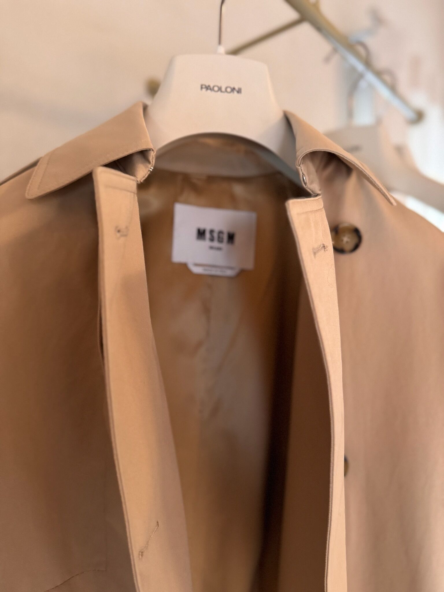 A beige shirt hanging on a hanger with a label reading "MSGN."