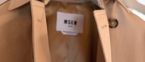 Una camisa color beige colgada en un perchero con una etiqueta que dice "MSGN".